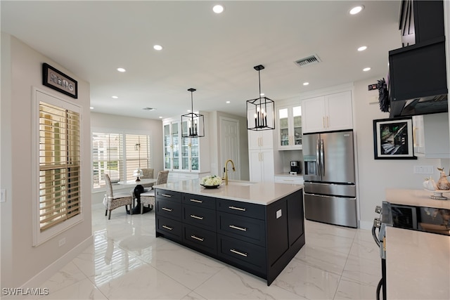 kitchen with hanging light fixtures, a center island with sink, sink, white cabinets, and appliances with stainless steel finishes