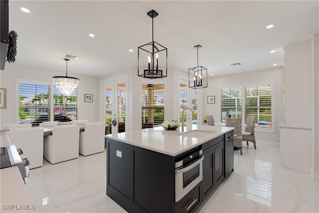 kitchen featuring a center island with sink, sink, appliances with stainless steel finishes, and hanging light fixtures