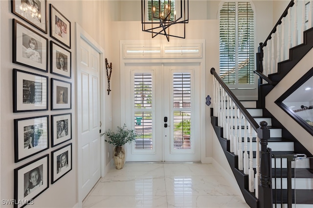 foyer entrance featuring a towering ceiling, french doors, and a notable chandelier