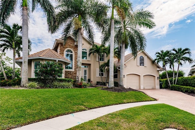 1045 Cottonwood Ct, Marco Island, FL 34145 - view of front of house featuring stucco siding, driveway, stone siding, and a front lawn