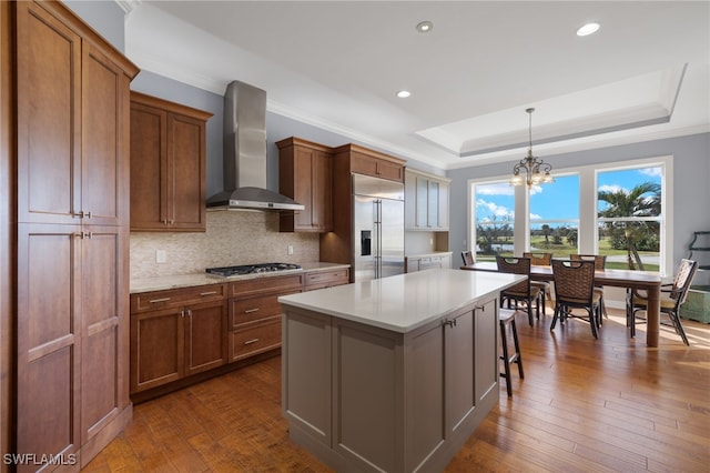 kitchen featuring a kitchen island, appliances with stainless steel finishes, wall chimney exhaust hood, and dark hardwood / wood-style floors