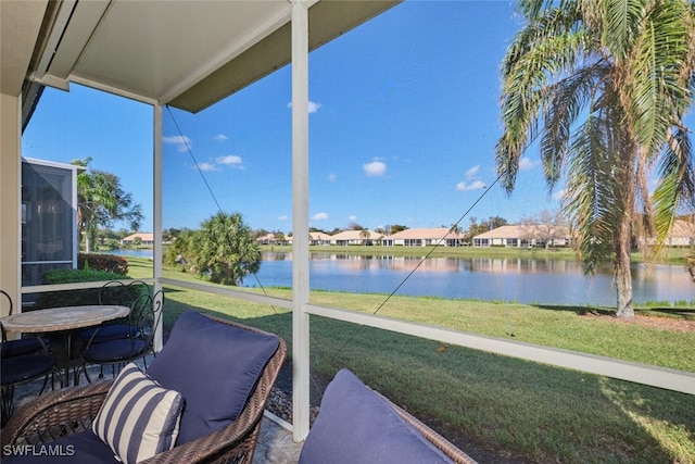 sunroom featuring a water view