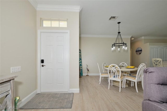 foyer entrance featuring crown molding, a chandelier, and light wood-type flooring