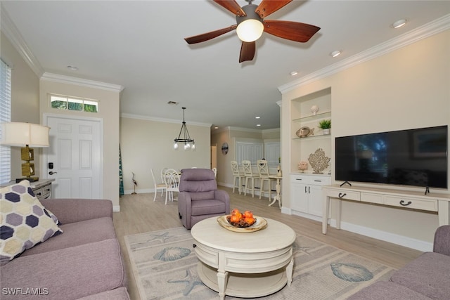 living room featuring ornamental molding, light hardwood / wood-style flooring, built in shelves, and ceiling fan with notable chandelier