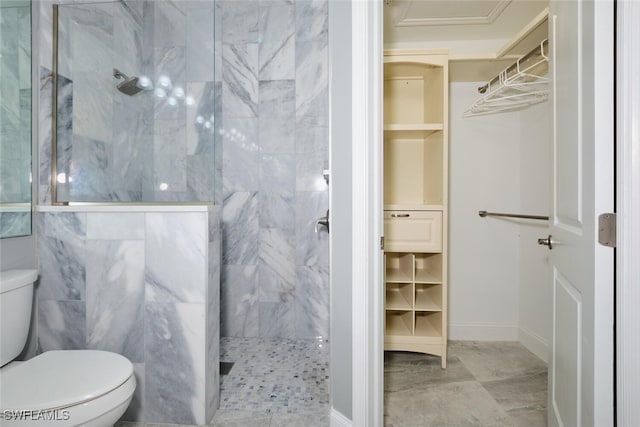 bathroom featuring a tile shower, toilet, and tile patterned flooring