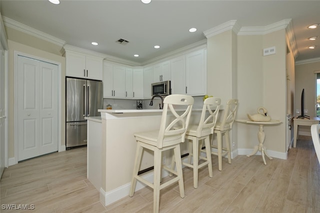 kitchen with light hardwood / wood-style floors, white cabinetry, and stainless steel appliances