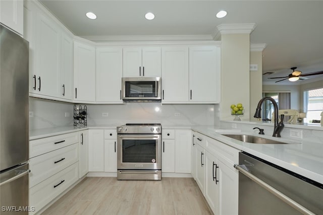 kitchen featuring appliances with stainless steel finishes, sink, ceiling fan, white cabinets, and ornamental molding