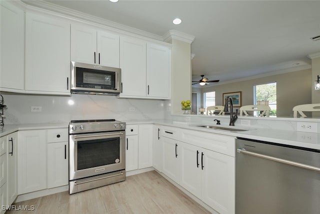 kitchen featuring sink, white cabinetry, ceiling fan, stainless steel appliances, and crown molding