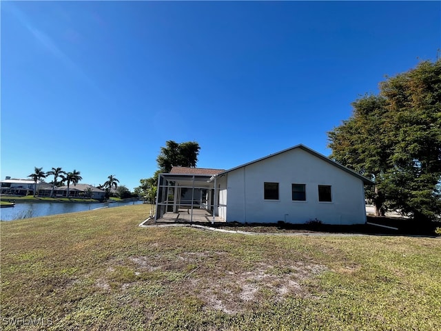 back of property featuring a yard, a water view, and a sunroom