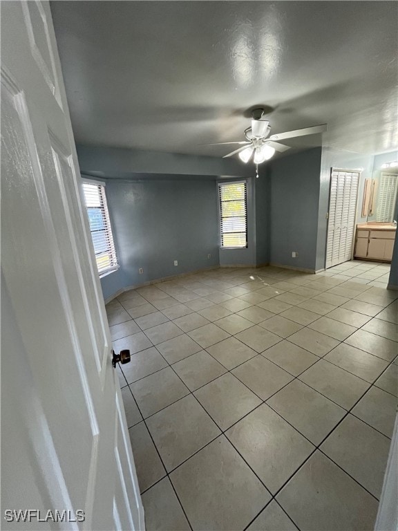 tiled spare room with ceiling fan