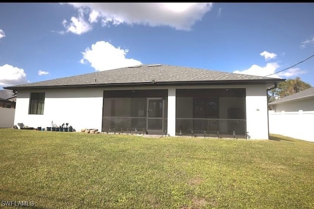 rear view of house featuring a lawn and a sunroom