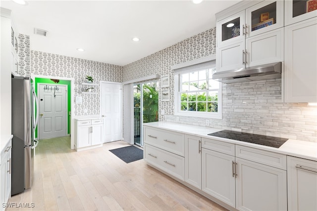 kitchen featuring stainless steel fridge, light wood-type flooring, white cabinetry, and black electric cooktop