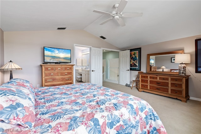 bedroom with ensuite bath, ceiling fan, light carpet, and vaulted ceiling