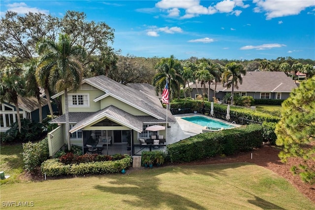 back of property with a fenced in pool and a yard