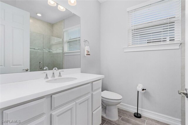 bathroom featuring toilet, a shower with door, and vanity