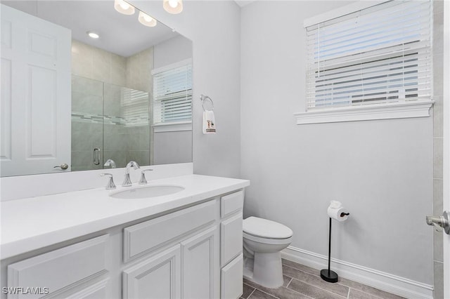 bathroom featuring toilet, a shower stall, baseboards, and vanity