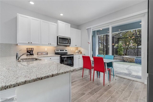 kitchen featuring decorative backsplash, sink, white cabinetry, light stone countertops, and appliances with stainless steel finishes