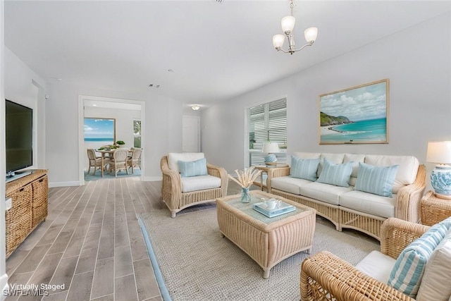 living room featuring a notable chandelier, baseboards, and wood finished floors