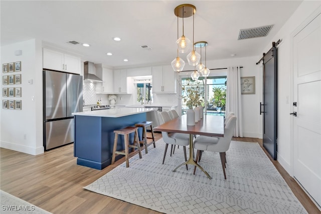 dining space featuring sink, a barn door, and light wood-type flooring