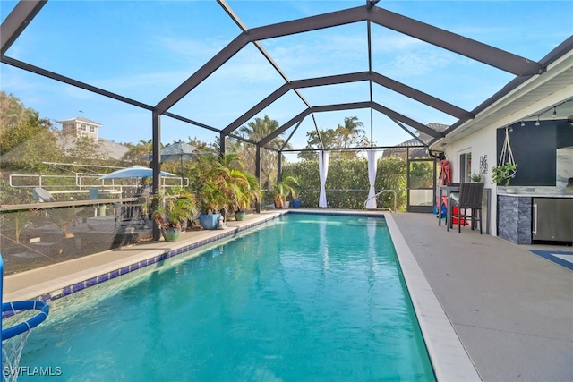 view of pool with a patio area and glass enclosure