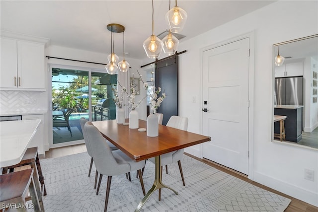 dining room with a barn door and light hardwood / wood-style floors