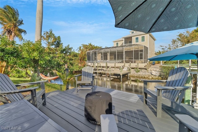 wooden deck featuring a boat dock, a water view, and a sunroom