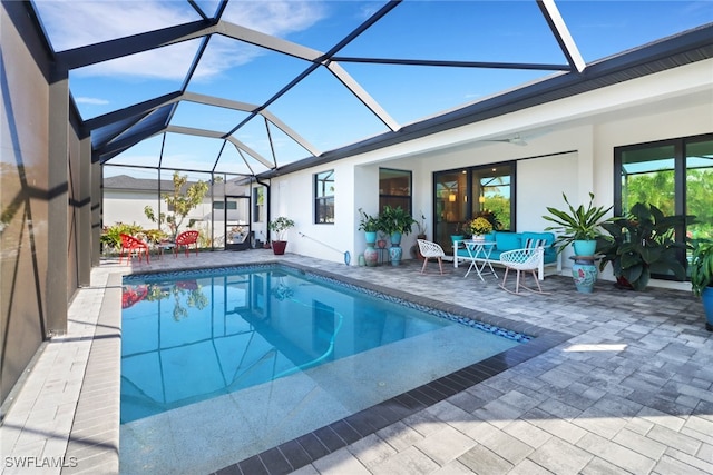 view of pool featuring glass enclosure, ceiling fan, and a patio