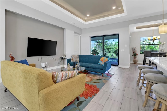 tiled living room with a chandelier and a tray ceiling