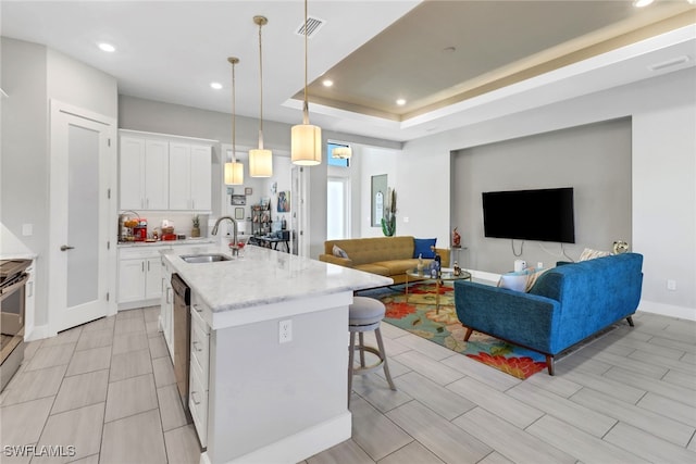 kitchen with a breakfast bar, sink, pendant lighting, a center island with sink, and white cabinets