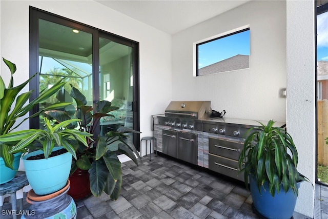 view of patio with a lanai, area for grilling, and exterior kitchen