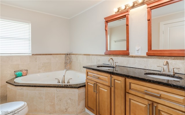 bathroom with vanity, tiled tub, and toilet