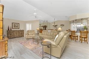 living room with vaulted ceiling, light hardwood / wood-style flooring, and ceiling fan with notable chandelier