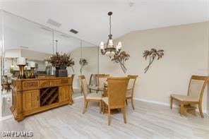 dining room with a notable chandelier, vaulted ceiling, and light wood-type flooring