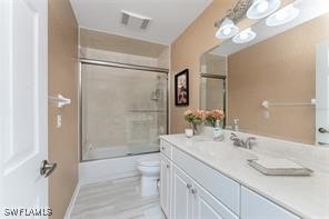 full bathroom featuring vanity, toilet, and bath / shower combo with glass door