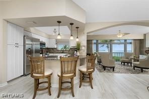 kitchen with white cabinetry, light hardwood / wood-style floors, decorative light fixtures, and kitchen peninsula