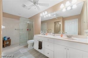 bathroom featuring vanity, toilet, walk in shower, and ceiling fan