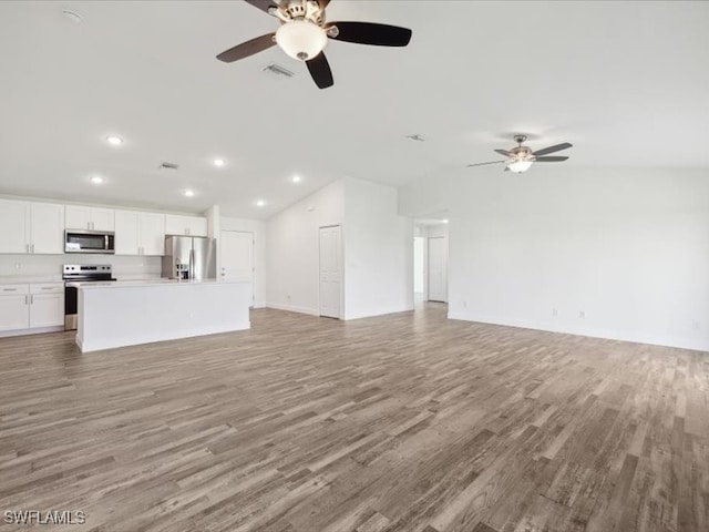 unfurnished living room featuring ceiling fan, light wood-type flooring, and vaulted ceiling