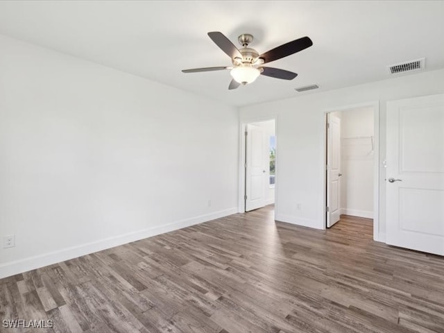 unfurnished bedroom with a closet, hardwood / wood-style floors, a spacious closet, and ceiling fan