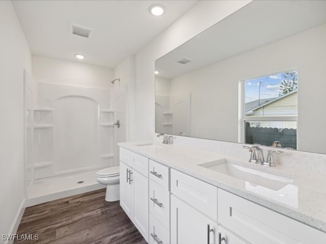 bathroom featuring vanity, toilet, hardwood / wood-style flooring, and a shower