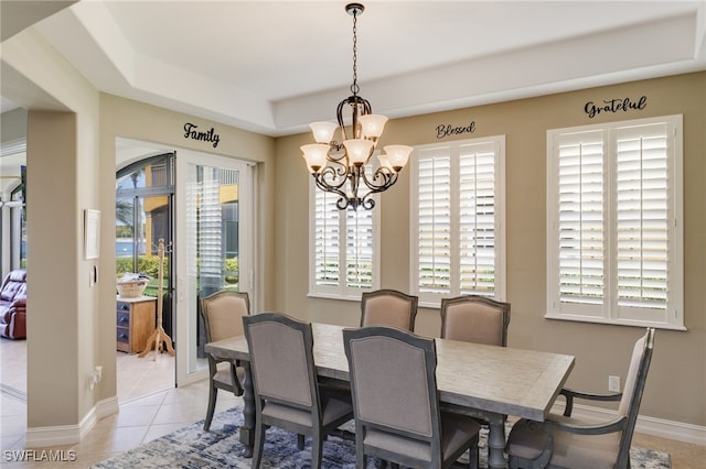 dining area with light tile patterned floors, baseboards, a raised ceiling, and an inviting chandelier