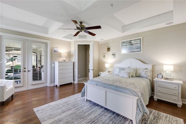 bedroom with access to outside, visible vents, a tray ceiling, and wood finished floors