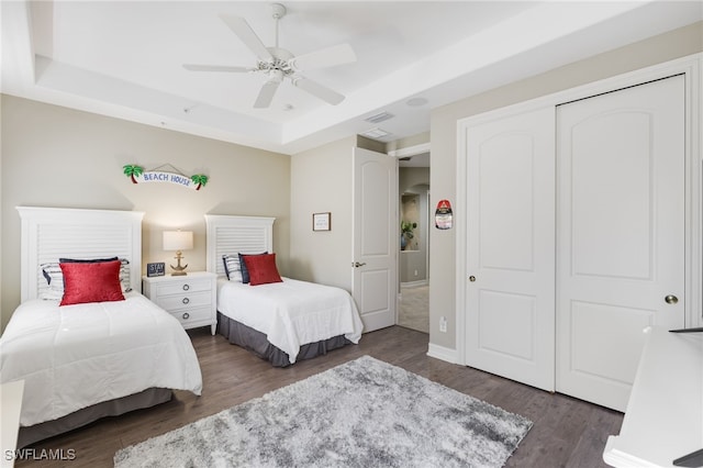 bedroom with a raised ceiling, visible vents, and wood finished floors