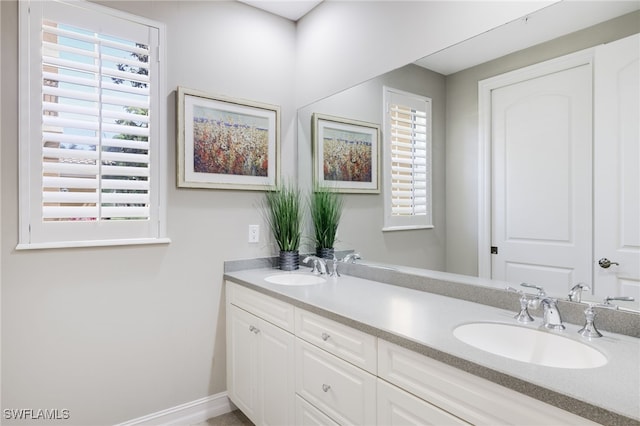 bathroom featuring a sink, baseboards, and double vanity