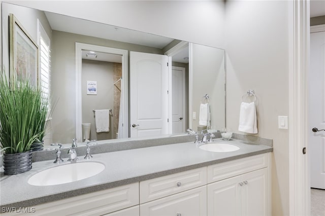 bathroom featuring double vanity, a sink, and toilet