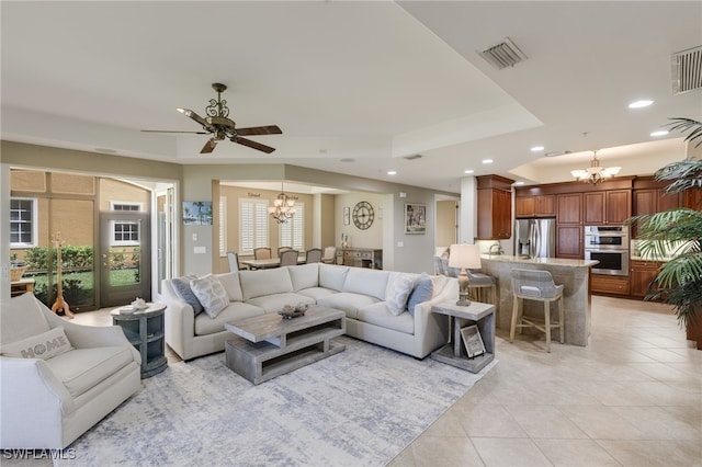 tiled living room featuring ceiling fan with notable chandelier