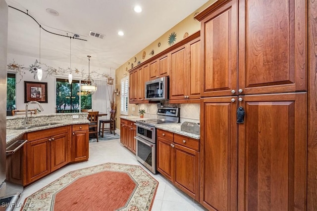 kitchen with decorative light fixtures, tasteful backsplash, sink, appliances with stainless steel finishes, and light stone counters