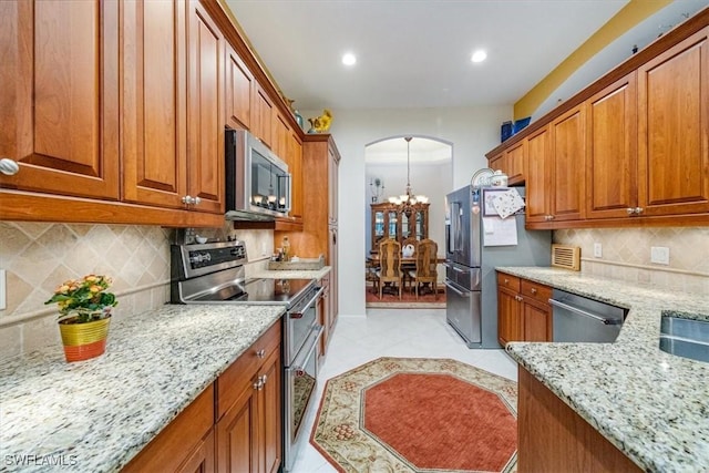 kitchen with decorative backsplash, light stone countertops, light tile patterned floors, and stainless steel appliances