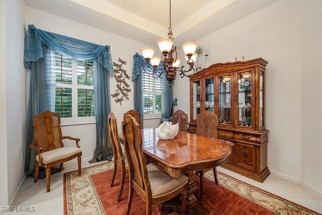 dining room featuring light tile patterned floors, a tray ceiling, ornamental molding, and an inviting chandelier