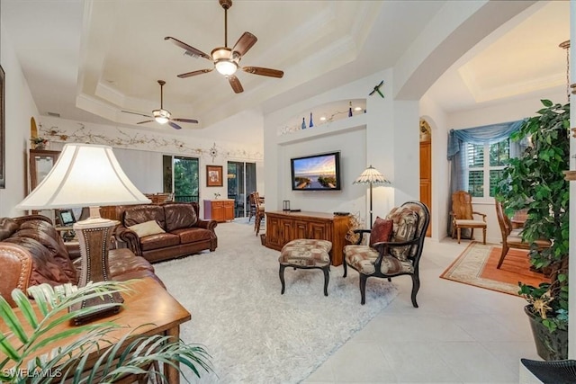 living room with ceiling fan, a tray ceiling, and built in shelves