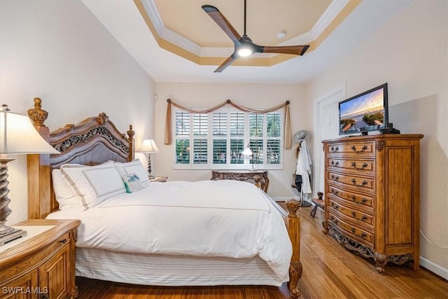 bedroom featuring ceiling fan, hardwood / wood-style floors, ornamental molding, and a raised ceiling